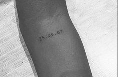 a black and white photo of a person's arm with the date tattooed on it