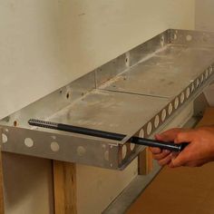 a person holding a tool in their hand near a metal shelf with holes on it