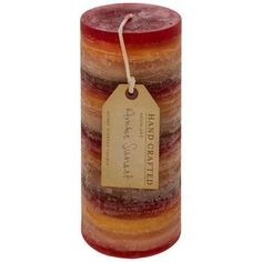 a red and orange candle with a tag on it