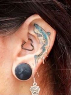 a woman's ear has a fish tattoo on it