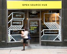 an open source hub store front on a city street with people walking in the doorway