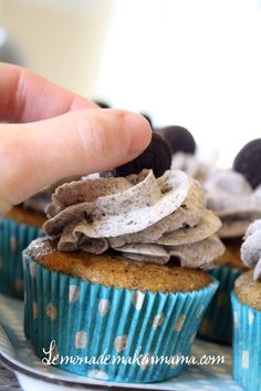 a hand is picking up some cupcakes on a plate