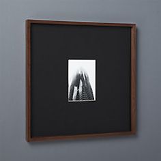 a black and white photo hanging on the wall next to a wooden frame with a building in it