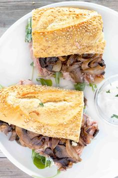 two sandwiches on a white plate with mushrooms and lettuce