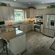 a large kitchen with stainless steel appliances and wood flooring is pictured in this image