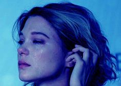 a close up of a person with her hand on her ear and the background is blue