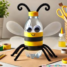 a plastic bottle with a bee on it sitting next to scissors and other craft supplies