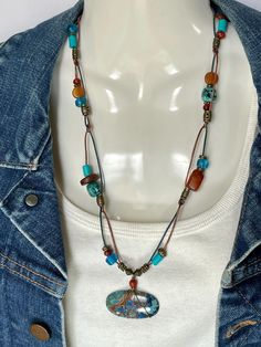 Shattuckite and Chrysocolla Cabochon wire wrapped with a Carnelian bead crown on bronze and turquoise 1mm leather cord. Mated with African Turquoise, Amber, Buffalo Bone, Carnelian, turquoise dyed bone, blue pony beads, and bronze metal beads. Bronze toggle to close. Cabochon is 1 5/8 x 3/4. Total necklace length is 24" with cabochon. No lead or nickel used. Please use the Last On, First Off approach. Stones discolor with lotions, perfumes, hairspray, sweat, chlorine, even some soaps, and will break if dropped. Casual Turquoise Beaded Necklaces For Festival, Bohemian Chrysocolla Beaded Necklace In Turquoise, Hippie Turquoise Healing Jewelry, Adjustable Hand-strung Turquoise Necklace, Adjustable Turquoise Chrysocolla Beaded Necklaces, Bohemian Turquoise Chrysocolla Necklace With Natural Stones, Adjustable Artisan Turquoise Necklace, Artisan Adjustable Turquoise Necklace For Beach, Adjustable Blue Hippie Necklace