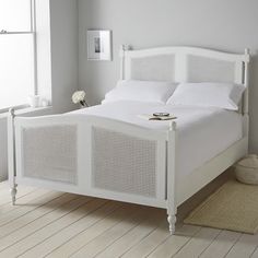 a white bed sitting in a bedroom next to a window