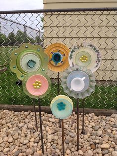 four colorful plates are sitting on top of each other in front of a chain link fence