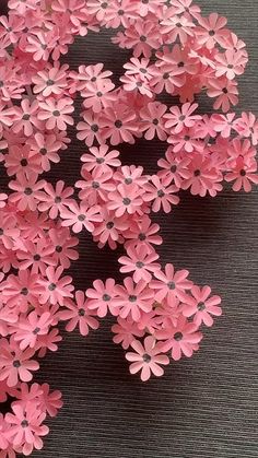 pink paper flowers are arranged in a circle on a table with black cloth behind them