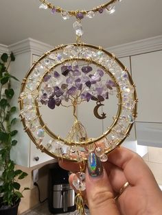 a person holding up a tree of life ornament in their hand with the moon and stars on it