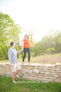 a man and woman standing on top of a stone wall