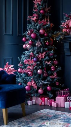 a decorated christmas tree with pink and purple ornaments in front of a blue velvet chair