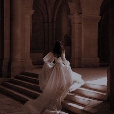 a woman in a white dress is walking up some stairs with her back to the camera