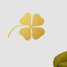 a green chair sitting next to a white wall with a four leaf clover on it