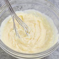 a glass bowl filled with cream and two whisks in it on a table