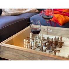 a glass of wine sitting on top of a table next to a wooden chess board