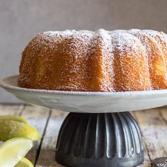 a bundt cake with powdered sugar on top and lemon wedges next to it