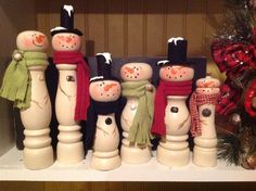 a group of snowmen standing next to each other on top of a shelf in front of a christmas tree