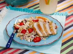 a blue plate topped with chicken, rice and tomatoes next to a glass of orange juice