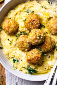 a white bowl filled with meatballs covered in gravy and garnished with parsley