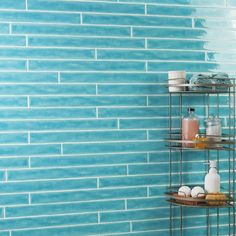 a bathroom with blue tiles and shelves holding soaps, shampoos, and other items