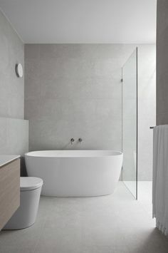 a white bath tub sitting next to a toilet in a bathroom