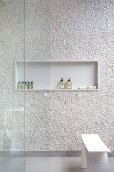 a white bench sitting in front of a wall mounted shelf next to a glass door