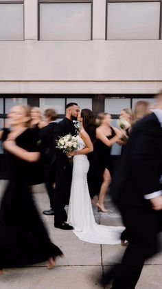 a bride and groom kissing in front of a group of people