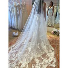 a woman standing in front of a mirror wearing a wedding dress with a long veil