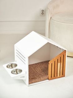 a white dog house with two bowls in it