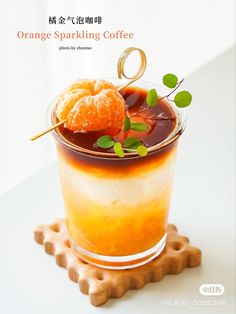 an orange sparkling coffee is served in a glass with garnishes and leaves