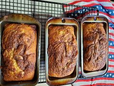 three loafs of bread sitting on top of a cooling rack next to an american flag