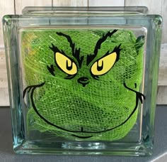 a glass block with a green creature drawn on it's face and yellow eyes