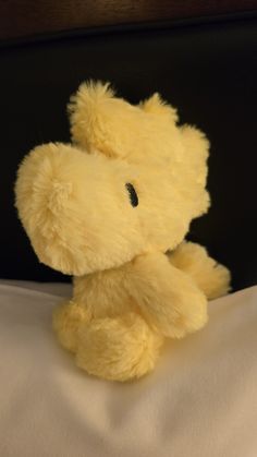 a yellow teddy bear sitting on top of a bed