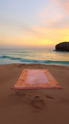 a blanket laying on top of a sandy beach next to the ocean