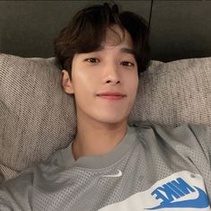 a young man laying on top of a couch next to a wall with the nike logo on it