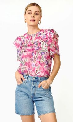 For a glamorous and whimsical look, this short-sleeve blouse provides all kinds of fun and folds. The collar is decorated with layers of ruffles that lay on the shoulders. Created from a light and airy chiffon, the print is inspired by spring flower fields overflowing with romantic pinks and purples, making the piece v Walking On Sunshine, Smocked Top, Ruffled Sleeve Top, Ruffle Shorts, Ruffle Collar, Floral Ruffle, Something Sweet, Chiffon Blouse, Go Ahead