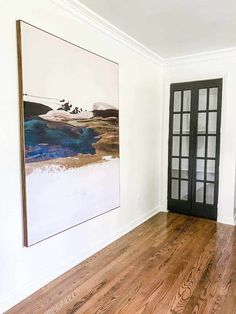 an empty room with wood floors and a painting hanging on the wall next to it