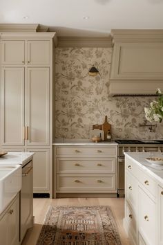 a kitchen with white cabinets and floral wallpaper