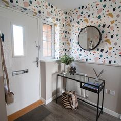 a room with a table, mirror and wallpaper on the walls that has different colors