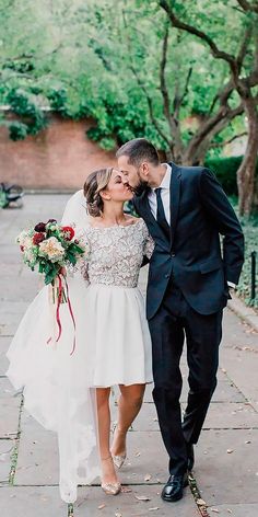 a bride and groom are walking down the sidewalk