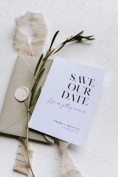 an envelope with a wax stamp and some white paper on it next to a plant