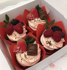 four cupcakes with chocolate, raspberries and strawberries in a box