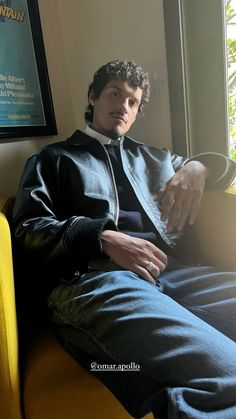 a man sitting on top of a yellow couch next to a window