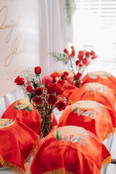 there are many red flowers in vases on the table with an orange cloth draped over them