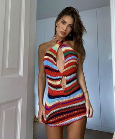 a woman in a multicolored dress posing for the camera with her hands on her hips