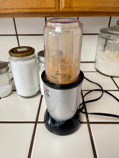 a blender sitting on top of a counter next to some jars and other items