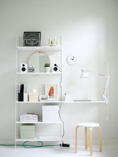 a white shelf with various items on it and a chair in the corner next to it